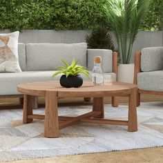 a wooden table sitting on top of a rug next to two couches and a potted plant