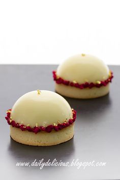 two cookies with white frosting and red sprinkles sitting on a table