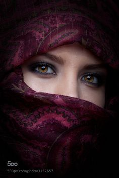 a woman with blue eyes wearing a purple shawl over her head and looking into the camera