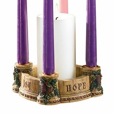 three purple candles sitting on top of a wooden stand with pine cones and holly wreaths