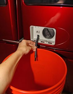 a person is holding the handle on a red bucket