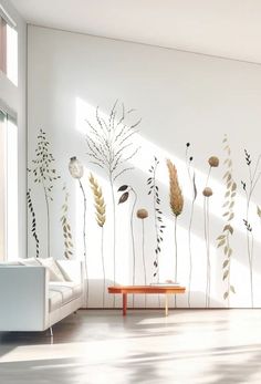 a living room with white walls and plants painted on it's wall, along with a coffee table