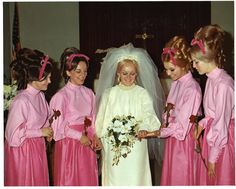 a group of women standing next to each other wearing pink dresses and holding bouquets