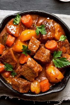 beef stew with carrots, potatoes and parsley in a cast iron skillet