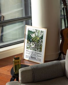 a room with a guitar, vase and other items on the floor in front of a window