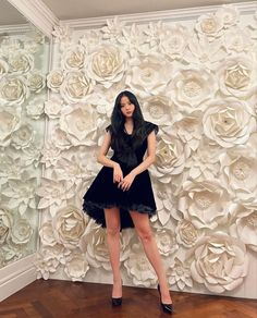 a woman standing in front of a wall with flowers on it