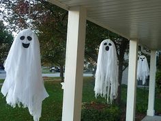 three ghost decorations hanging from the side of a house