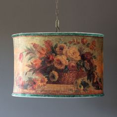 a lamp shade with flowers painted on it hanging from a ceiling fixture in a room