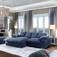 a living room filled with blue couches and furniture in front of two large windows