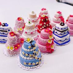 there are many small cakes on the table with different colors and designs, including pink, blue, red, yellow