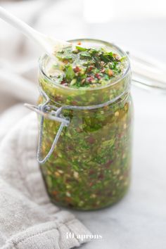 a jar filled with food sitting on top of a white cloth next to a spoon