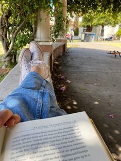 someone is laying down reading a book outside