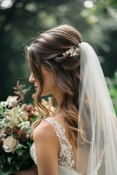 a woman in a wedding dress with a veil on her head and flowers in her hair