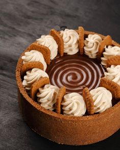 a chocolate cake topped with whipped cream and pretzel pieces on a black table