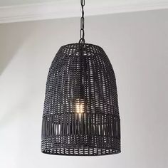 a light hanging from the ceiling in a room with white walls and black wicker