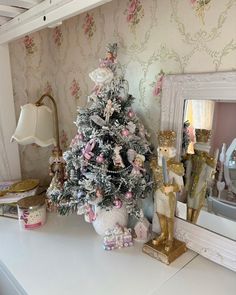 a white christmas tree sitting on top of a table next to a mirror and lamp