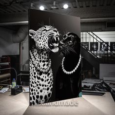 a black and white photo of two leopards with pearls on their necks, one is touching the other's face