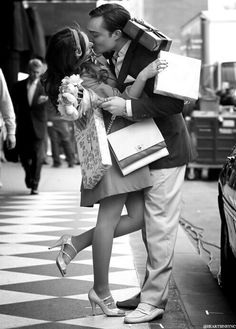 a man kissing a woman on the cheek while holding shopping bags in front of him