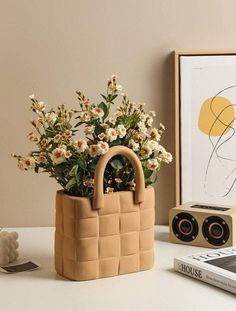 a planter with flowers in it sitting on a table next to a book and radio