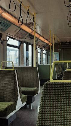 the interior of a subway car with green seats and yellow railings on each side