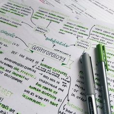 two pens are sitting on top of a paper with writing in green and white ink