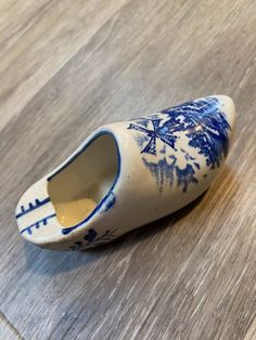 a blue and white porcelain shoe sitting on top of a wooden floor next to a wall