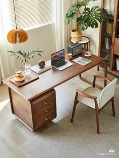 a wooden desk with a laptop on top of it next to a chair and potted plant