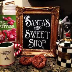 there is a sign that says santa's sweet shop next to some cookies and coffee