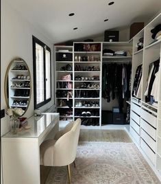 a walk in closet with white shelving and lots of shoes