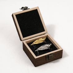 an open wooden box with some metal items in it on a white surface and the lid opened