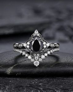 a black and white diamond ring sitting on top of a piece of stone with diamonds around it