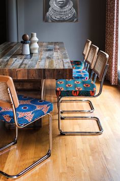 a wooden table with four chairs and a painting on the wall above it in a dining room