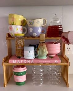 there is a shelf with cups and other items on it, along with mugs