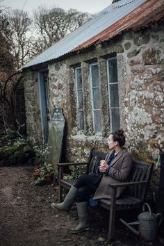 a woman sitting on a bench in front of an old building