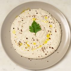 a white plate topped with a hummus covered in sauce and garnished with parsley