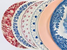 several plates are stacked on top of each other in different colors and patterns, one is pink, the other is blue