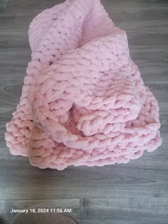 a pink knitted blanket laying on top of a wooden floor