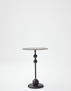 a small round table with two black balls on the top and one white ball at the base