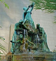 a fountain with statues on it in front of a building