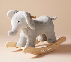 a white stuffed elephant sitting on top of a wooden rocking toy with the word parker written across it