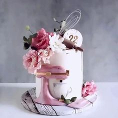 a white cake with pink flowers on top and a whisk in the middle