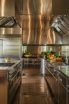 an industrial kitchen with stainless steel appliances and counter tops, including fruits and vegetables on the counters