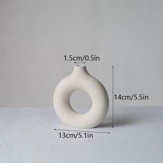 a white vase sitting on top of a table next to a measuring tape measure line