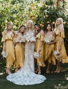 a group of women standing next to each other in front of an orange tree holding bouquets