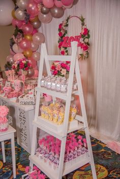 a table filled with lots of pink and white desserts on top of tables next to balloons