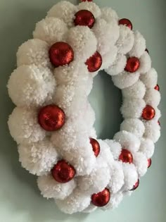 a white wreath with red ornaments hanging on the wall