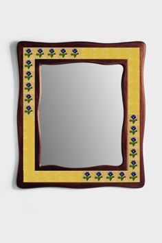 a mirror that is on the wall with blue flowers and leaves painted on it's sides