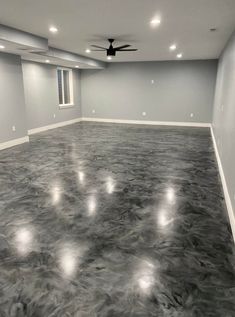 an empty room with gray walls and ceiling fans in the center is lit by recessed lights