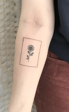 a small flower tattoo on the left inner arm and wrist, with a square frame around it