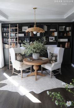 two chairs and a table in a room with bookshelves on the far wall